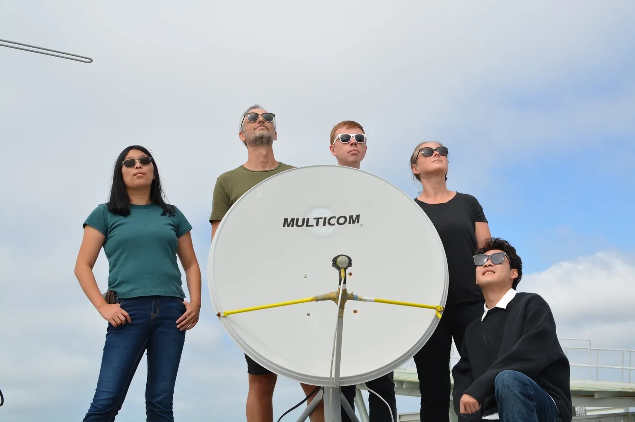 The researchers stand with their satellite receiver.